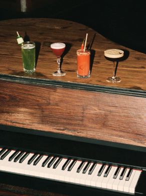 Serveur portant une lampe &agrave; bout de bras au-dessus d'une tabl&eacute;e en soir&eacute;e, lumi&egrave;re ambr&eacute;e &ndash; piano club La Sauvageonne, Ramatuelle